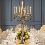 The Gillian Suite at Mercure Livingston Hotel, set up for a wedding breakfast, pretty blue painted wood panelling, yellow sashes, white linen, silver candlestick