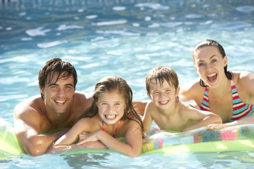 Young Family Relaxing In Swimming Pool Together